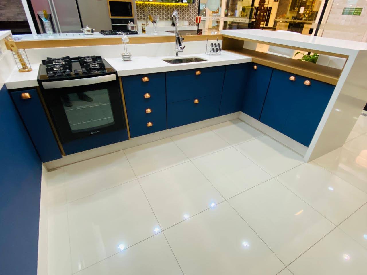 Uma cozinha com armários azuis e bancadas brancas