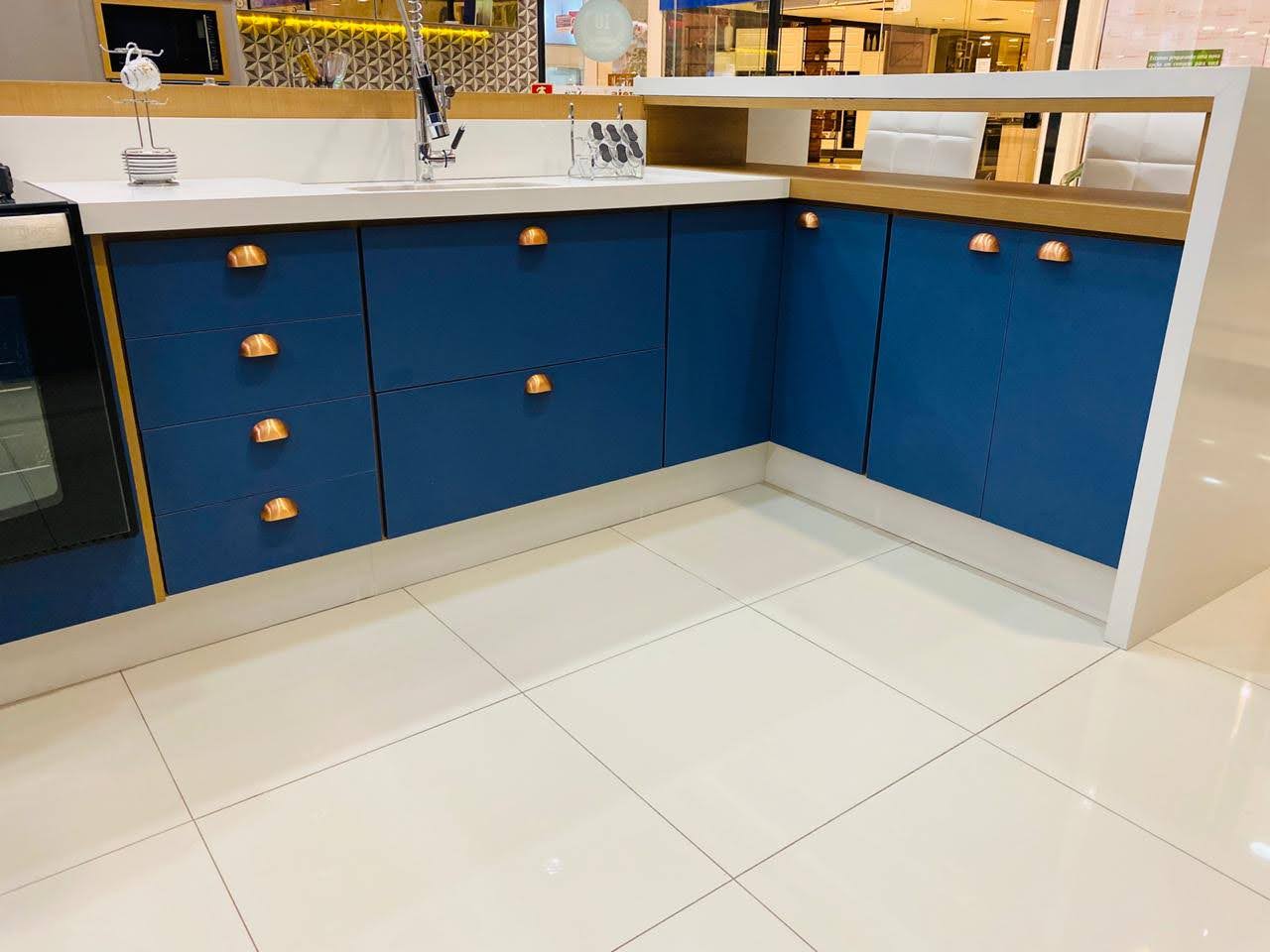 Uma cozinha com armários azuis e bancadas brancas.