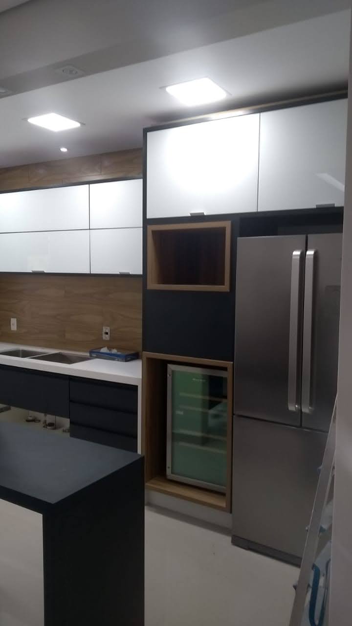 Uma cozinha com eletrodomésticos de aço inoxidável e armários brancos