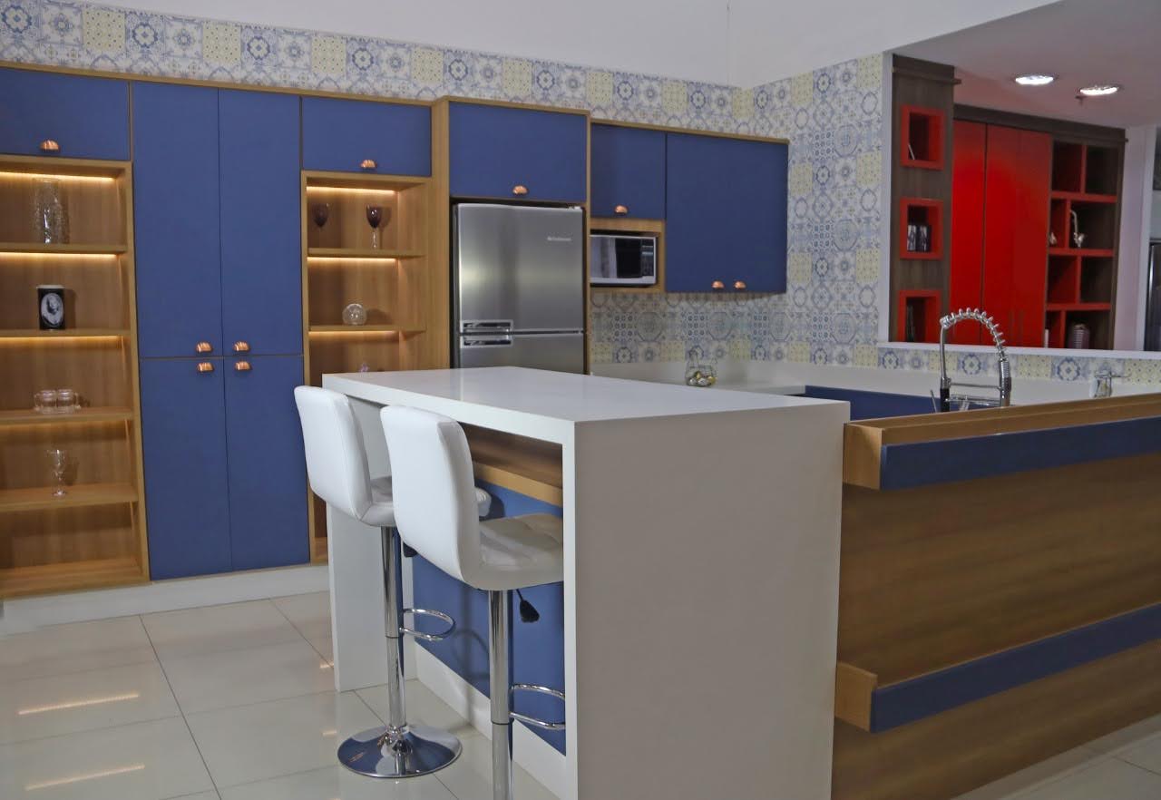 Uma cozinha com armários azuis, geladeira, pia e bar.