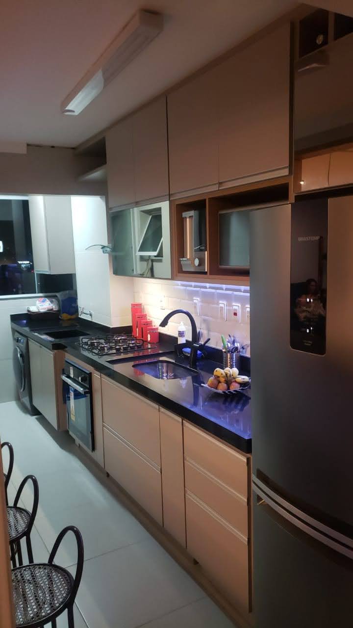 Uma cozinha com geladeira, fogão, pia e lava-louças.