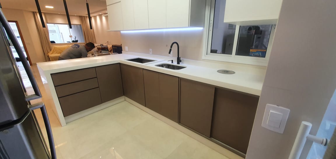 Uma cozinha com pia, geladeira e armários.