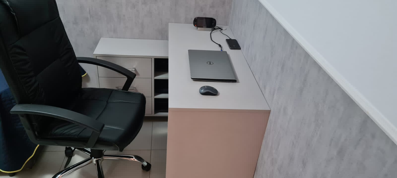 Uma cadeira está em frente a uma mesa com um laptop sobre ela.