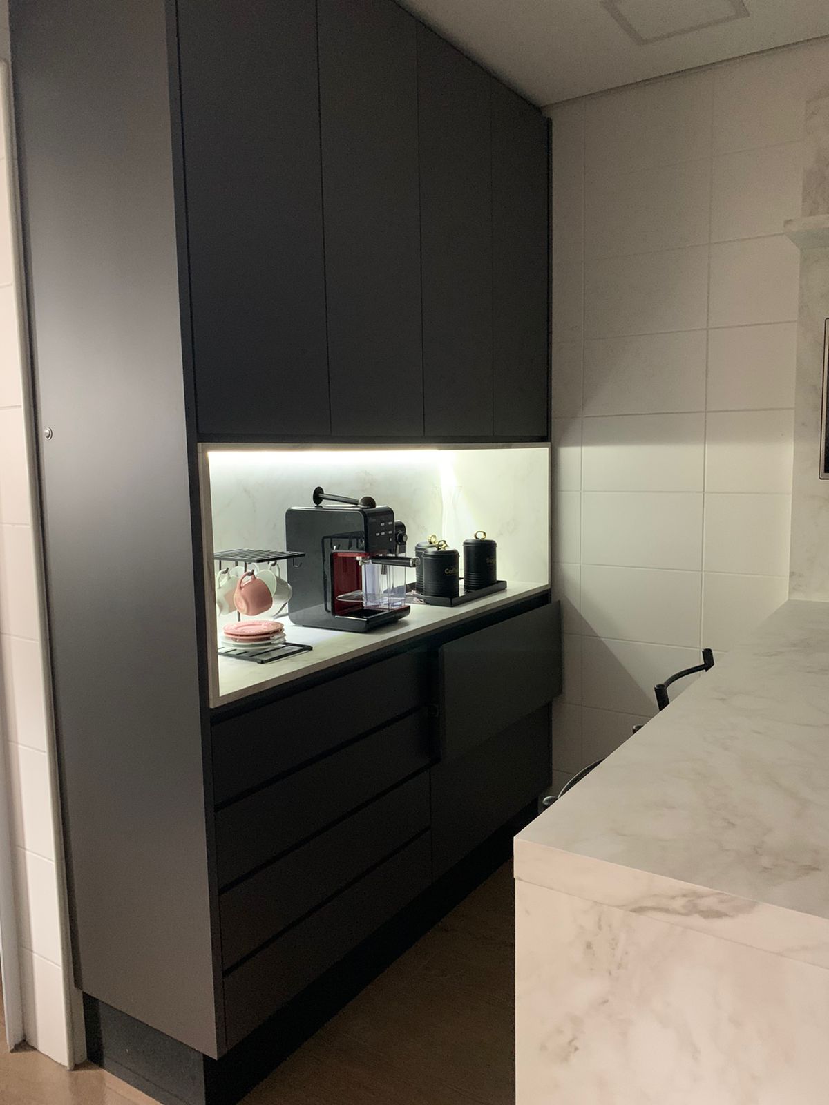 Uma cozinha com armários pretos e bancada branca.