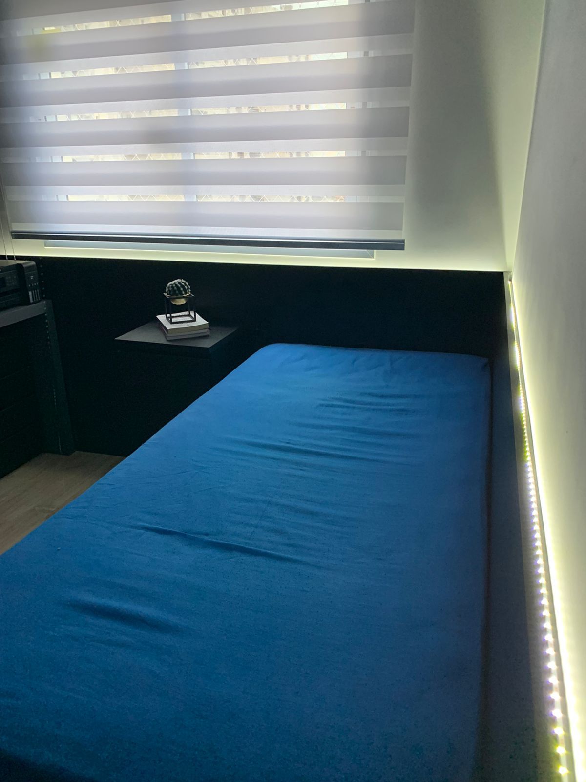 Um quarto com uma cama azul e uma janela