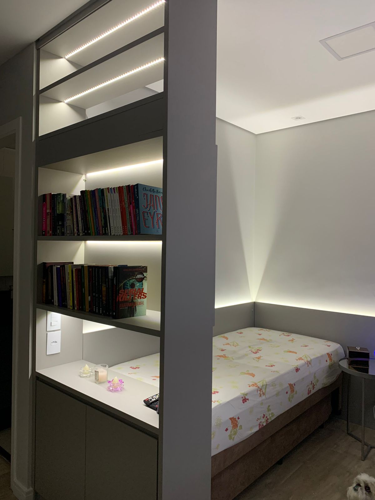 Um quarto com uma cama e uma estante com livros.