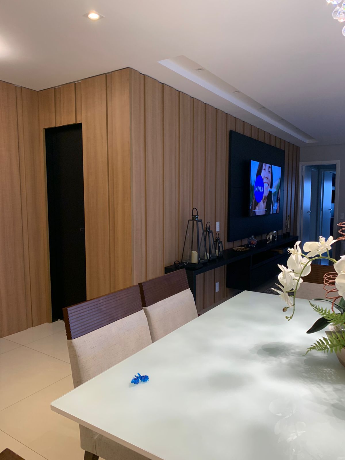 Uma sala de jantar com mesa e cadeiras e uma televisão na parede.