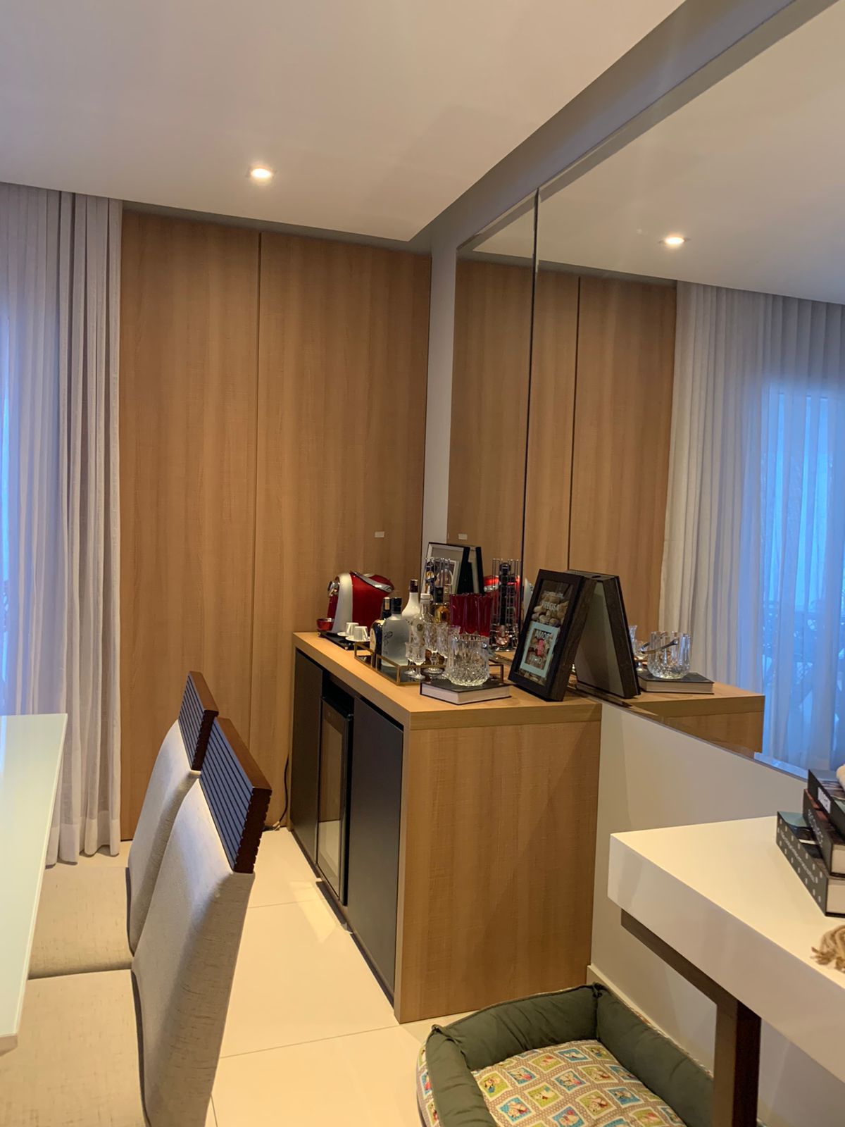 Uma sala de jantar com mesa, cadeiras, cama de cachorro e espelho.