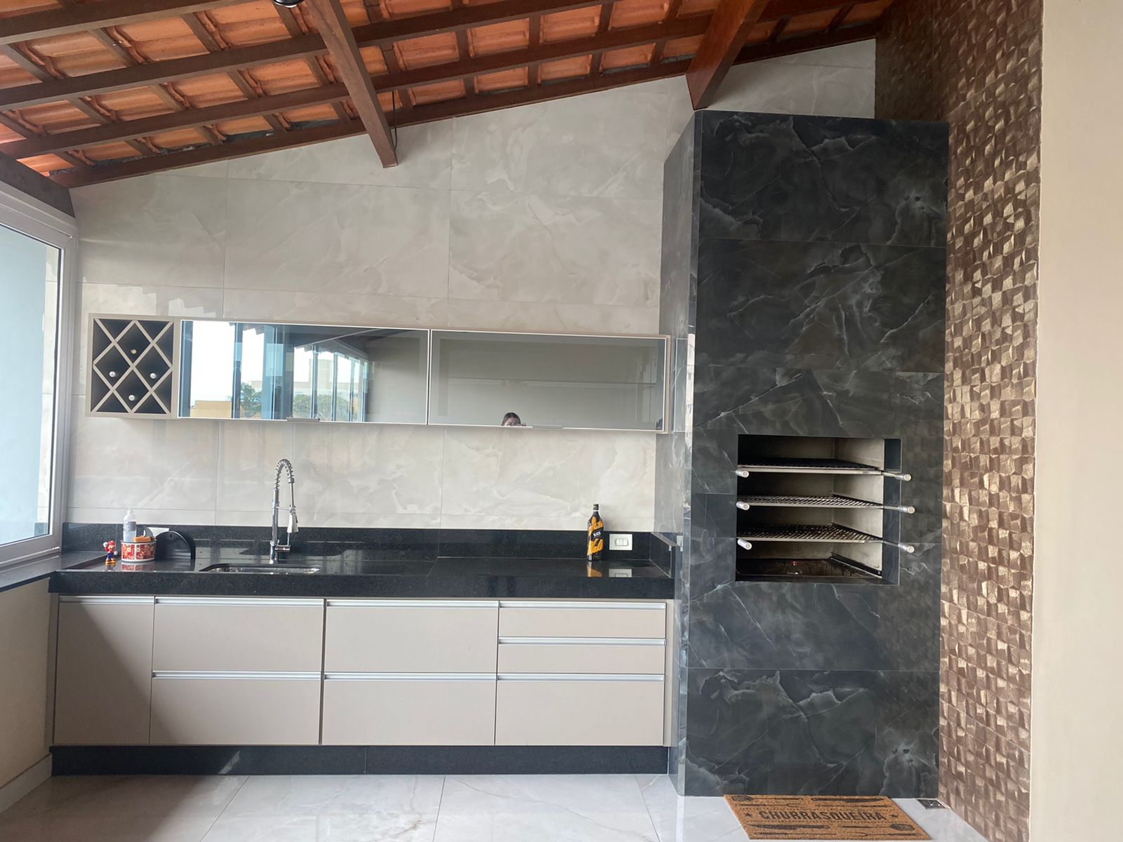 Uma cozinha com pia, armários e churrasqueira.