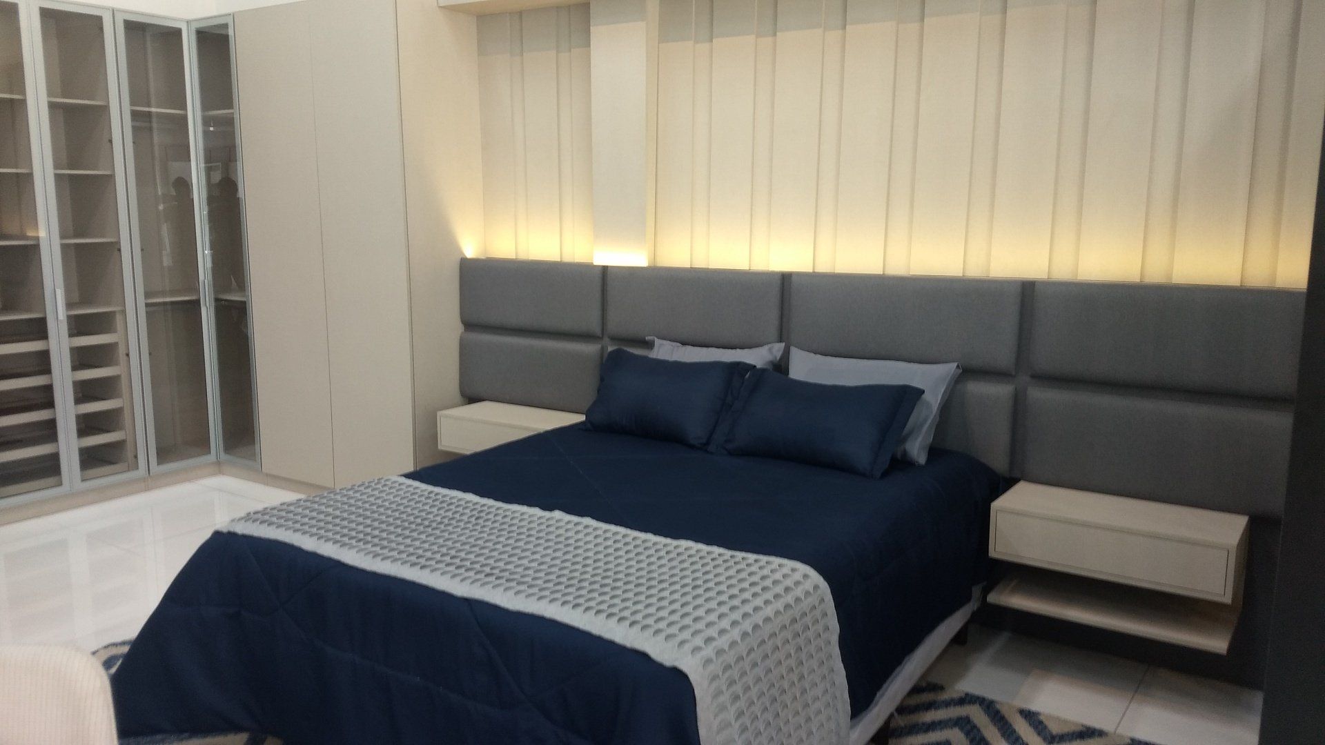 Um quarto com cama, mesinhas de cabeceira e armário.