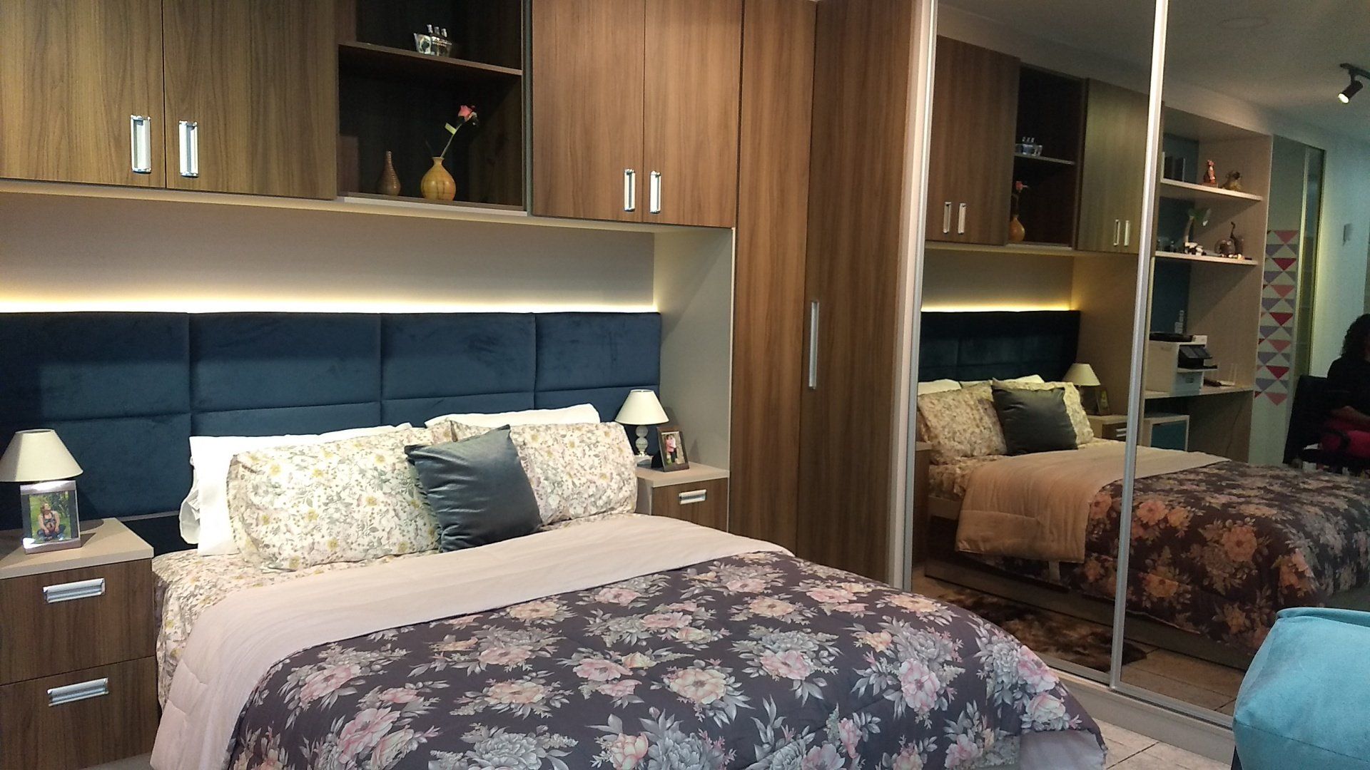 Um quarto com cama, mesinhas de cabeceira, armários e espelho.