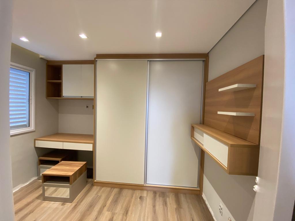 Uma sala com secretária, portas de correr, estantes e janela.