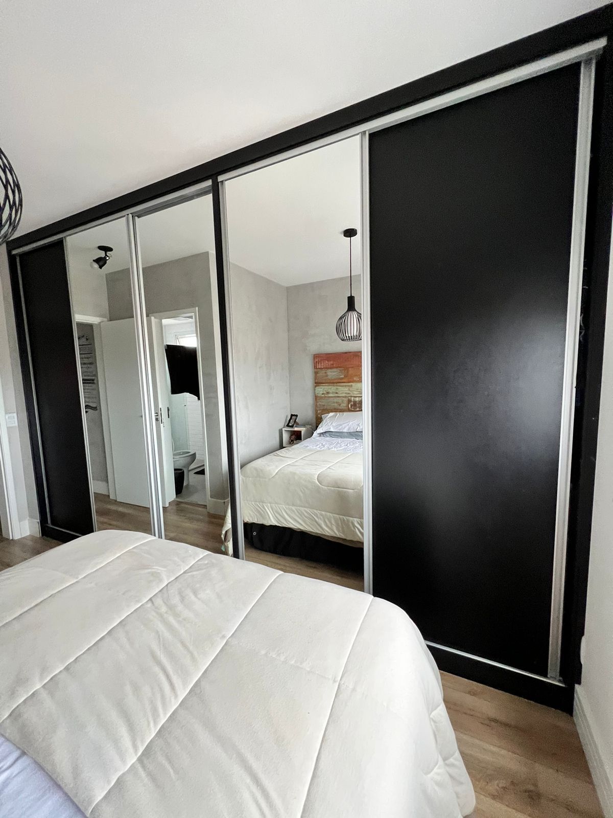 Um quarto com cama, espelhos e portas de correr.