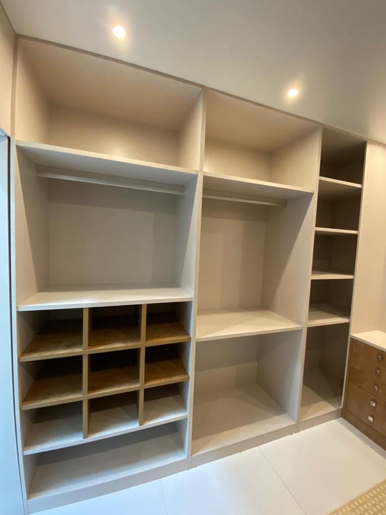 Um closet com muitas prateleiras e roupas penduradas.