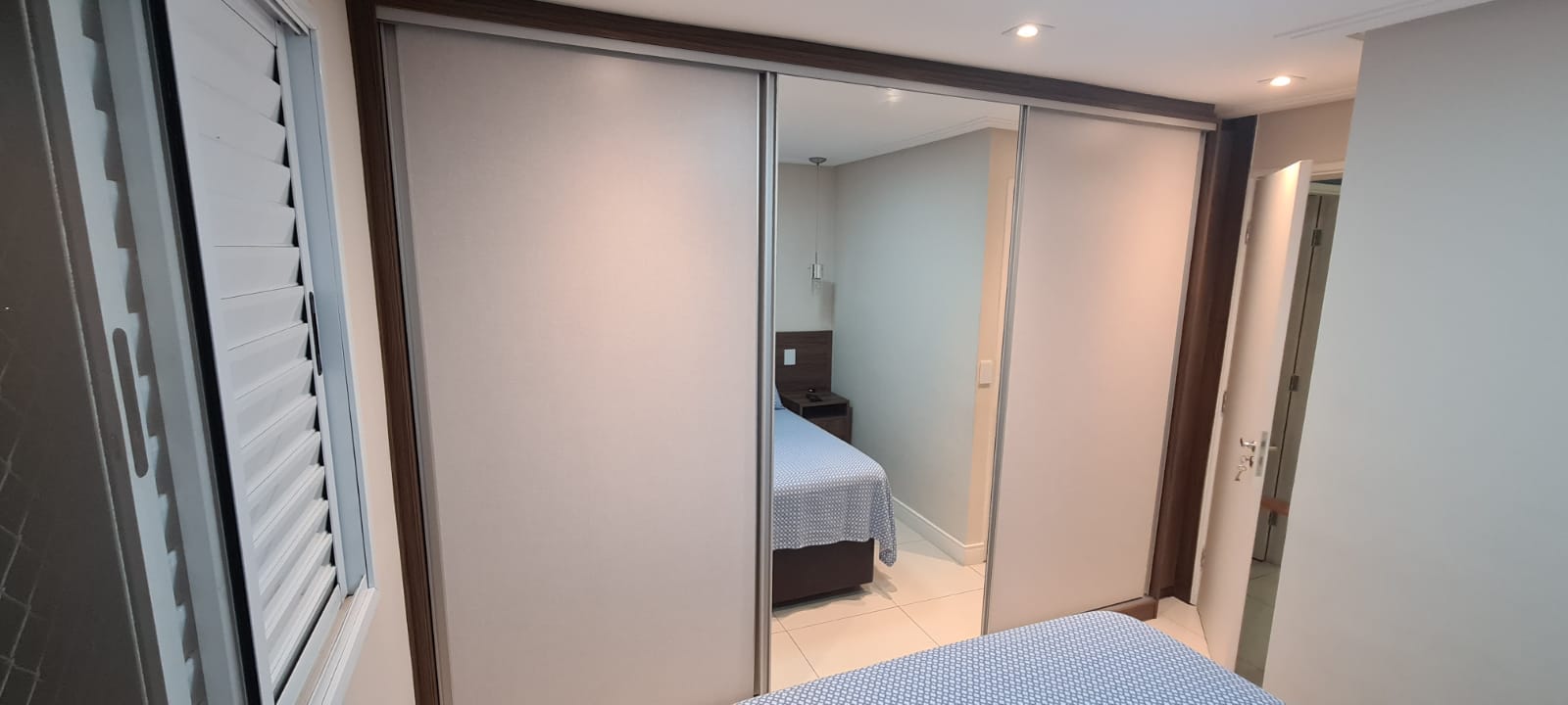 Um quarto com cama e um grande guarda-roupa com portas de correr.