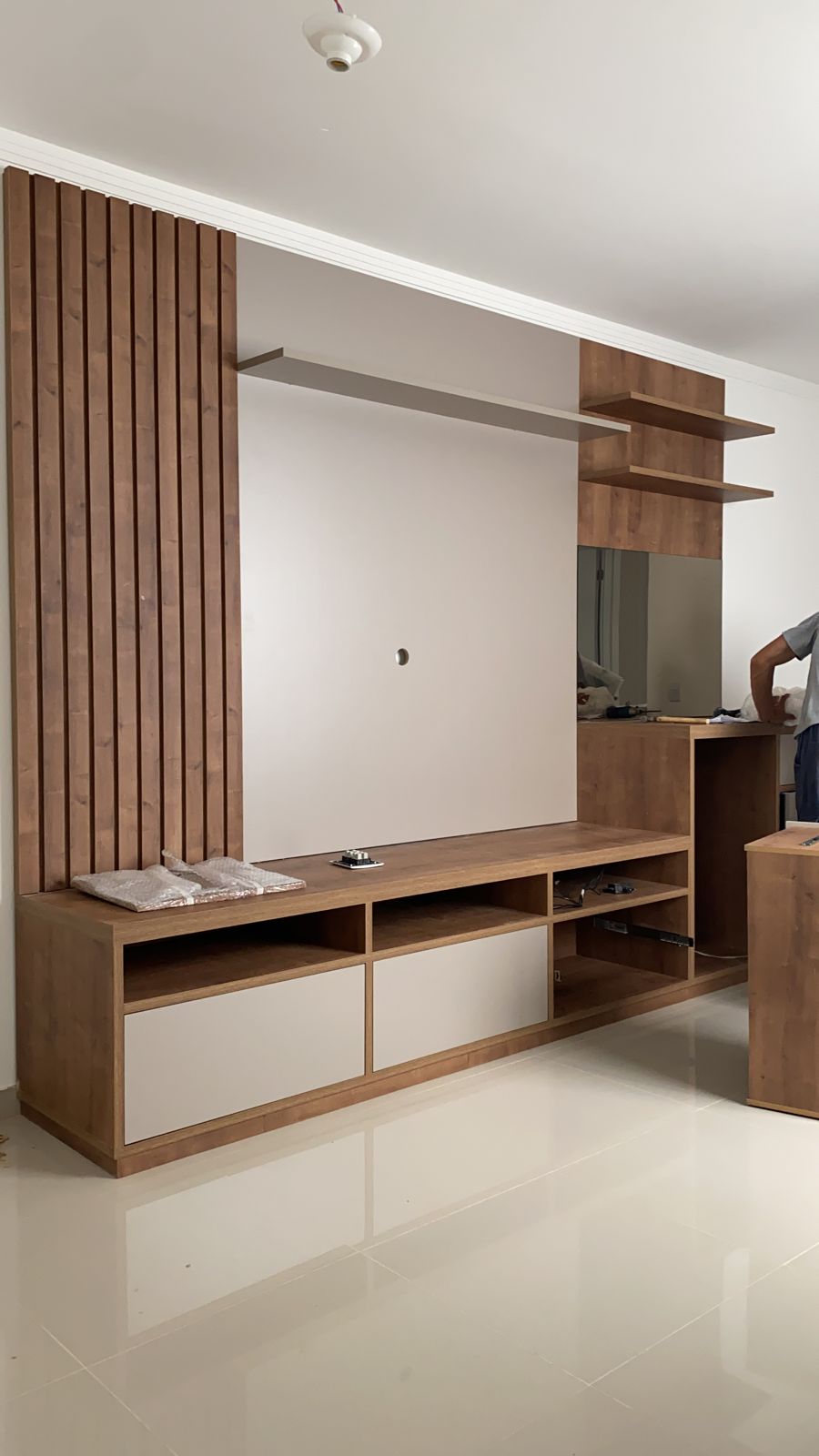 Uma sala de estar com centro de entretenimento em madeira e espelho.