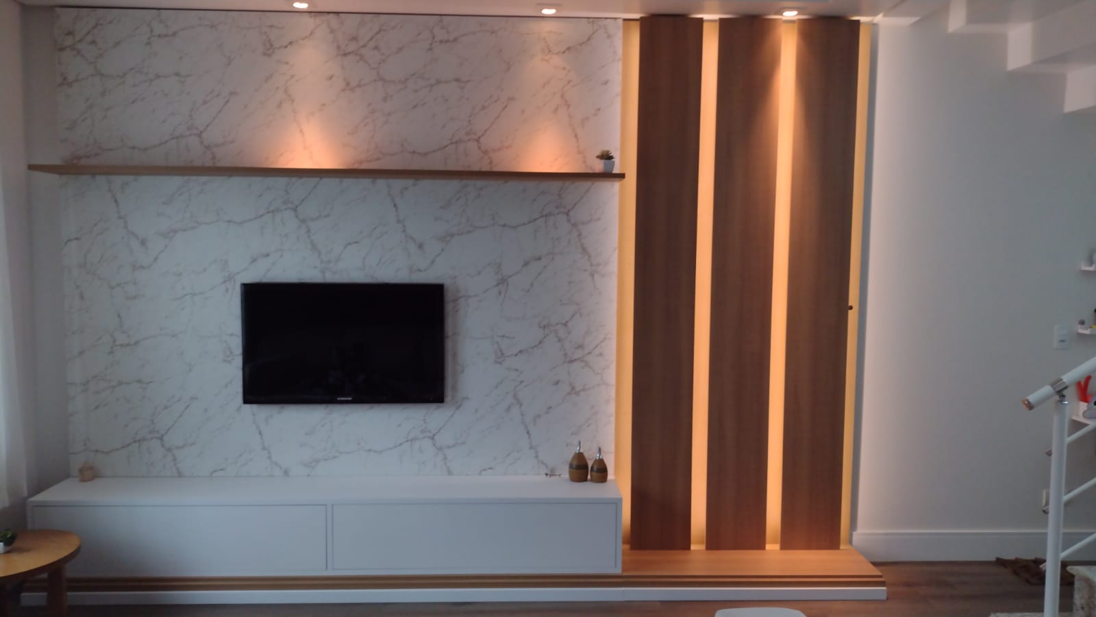 Uma sala de estar com TV de tela plana montada na parede.