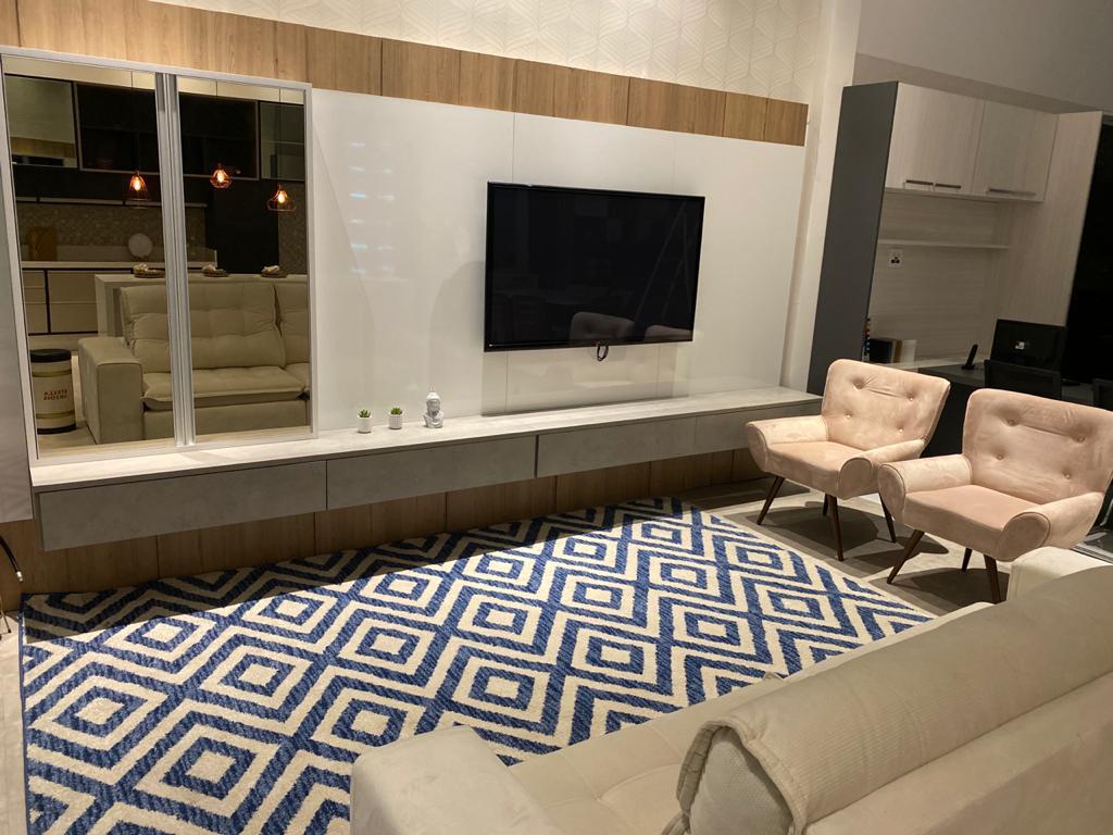 Uma sala com sofá, cadeiras, tapete e TV de tela plana.