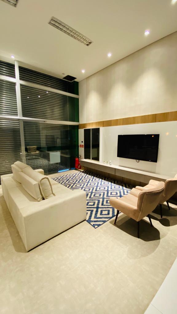 Uma sala de estar com sofá, cadeira e televisão.