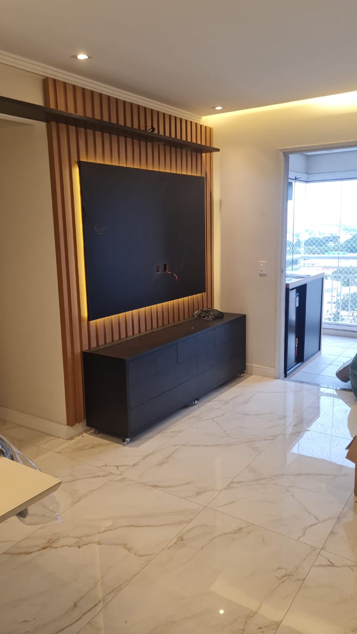 Uma sala de estar com TV de tela plana na parede e piso de mármore.