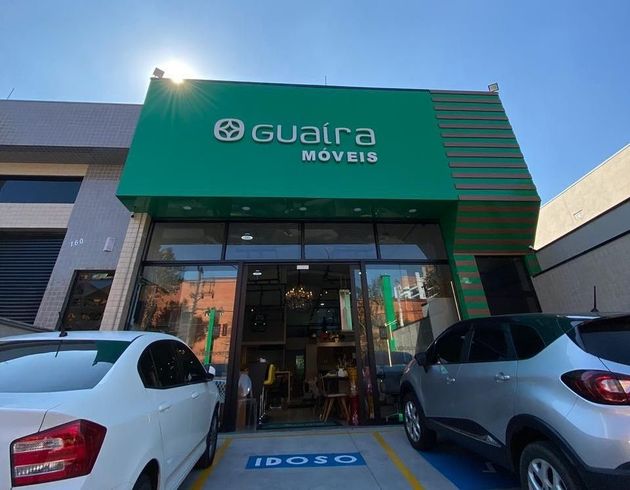 Dois carros estão estacionados em frente a uma loja chamada guarra moveis