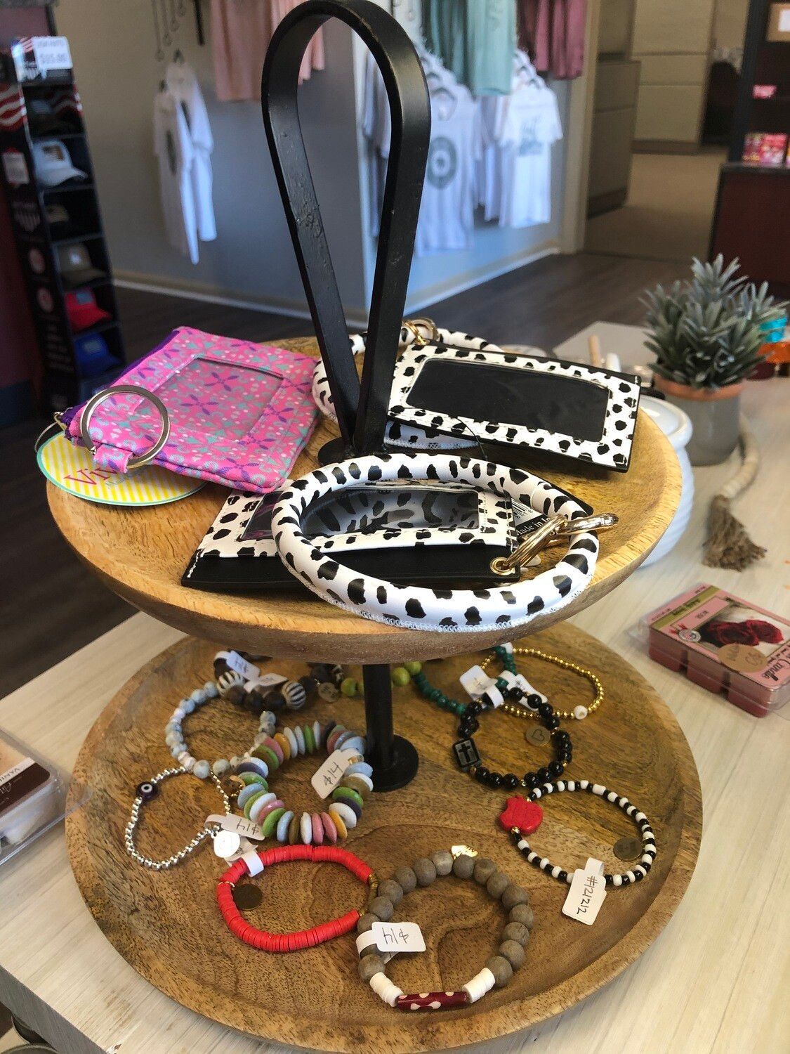 A wooden tray filled with bracelets and wallets on a table.