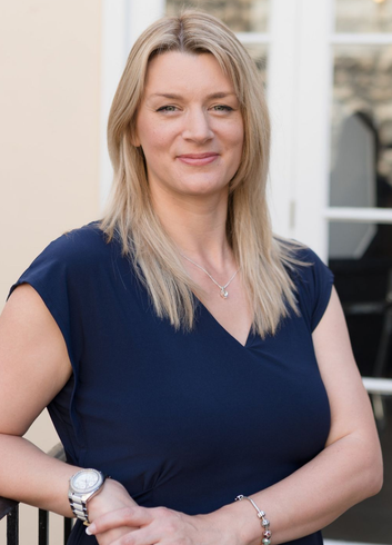 Kelly stands facing the camera and smiling