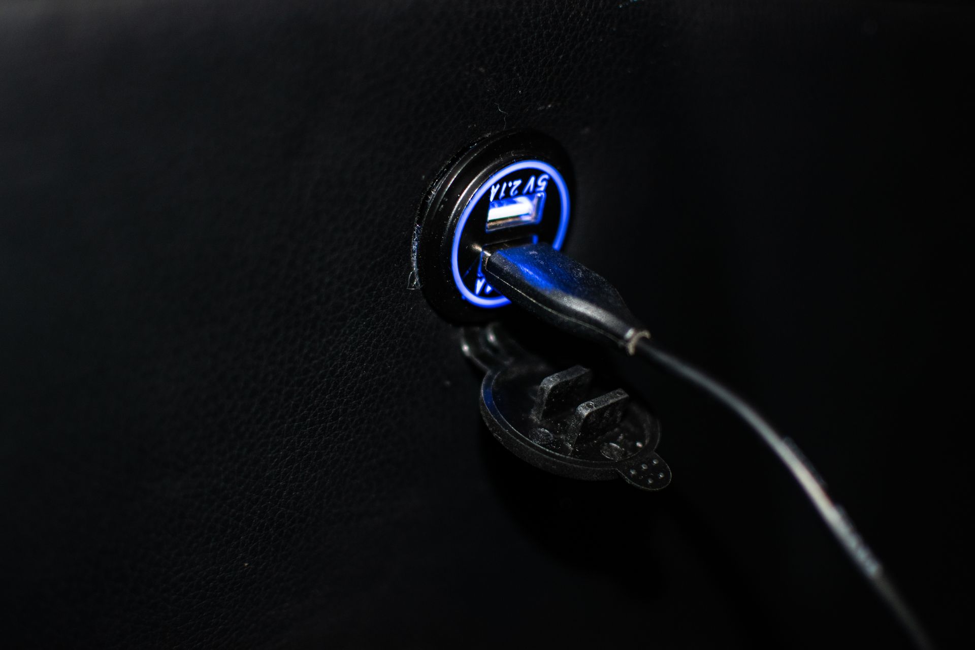 A close up of a car charger with a blue light on it.