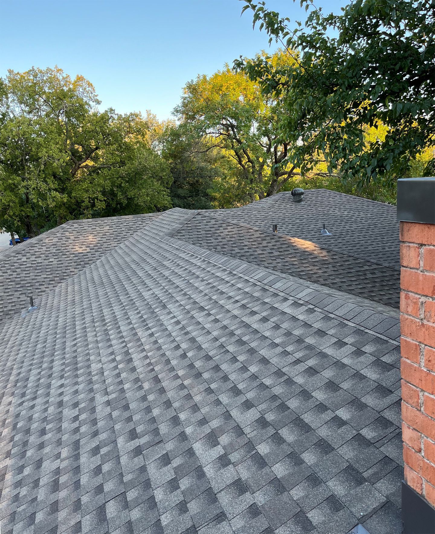 White flat roof overlooking a rural landscape with buildings, trees, and a clear blue sky.