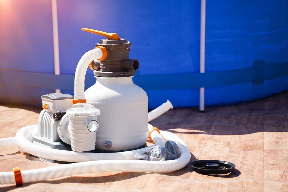 A Sand Filter is Sitting on the Ground in Front of a Swimming Pool — Pool Maintenance in Pacific Heights, QLD