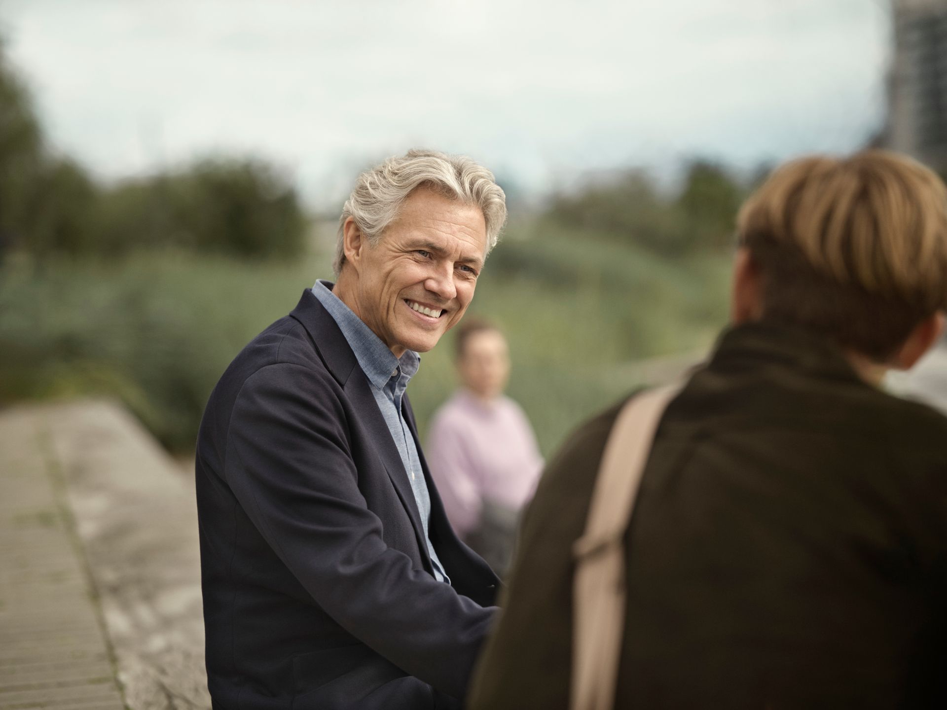 Un uomo in giacca e cravatta sorride mentre parla con un altro uomo.