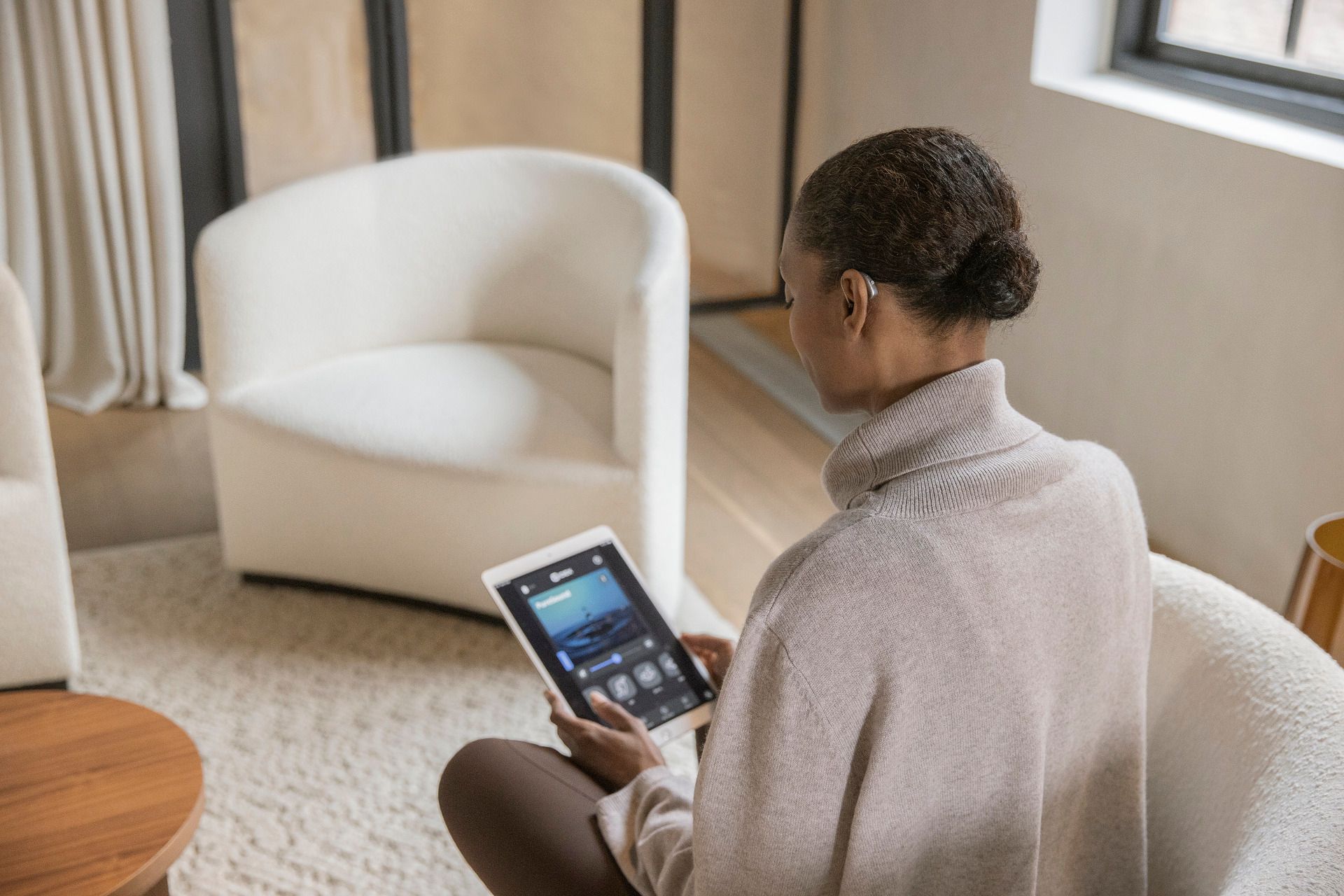 Una donna è seduta su una sedia e usa un tablet.