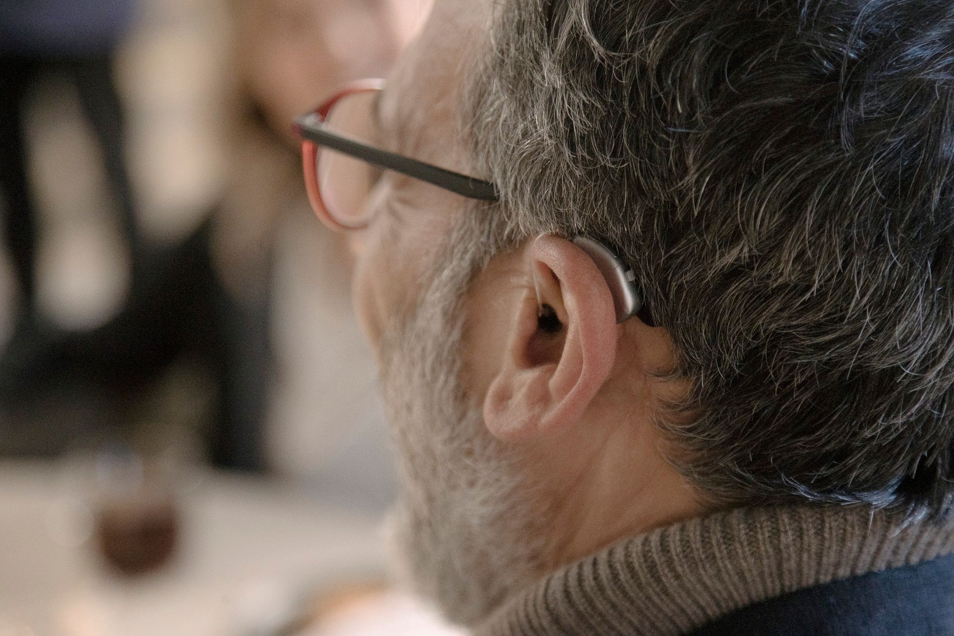 Un uomo con gli occhiali e un apparecchio acustico nell'orecchio.