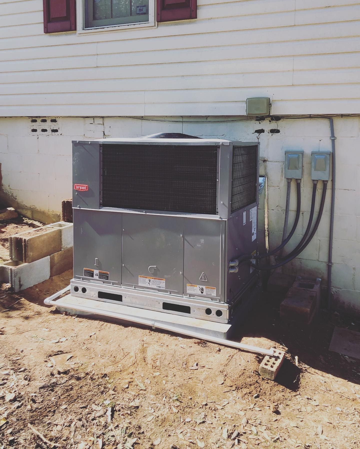 A large air conditioner is sitting outside of a house.