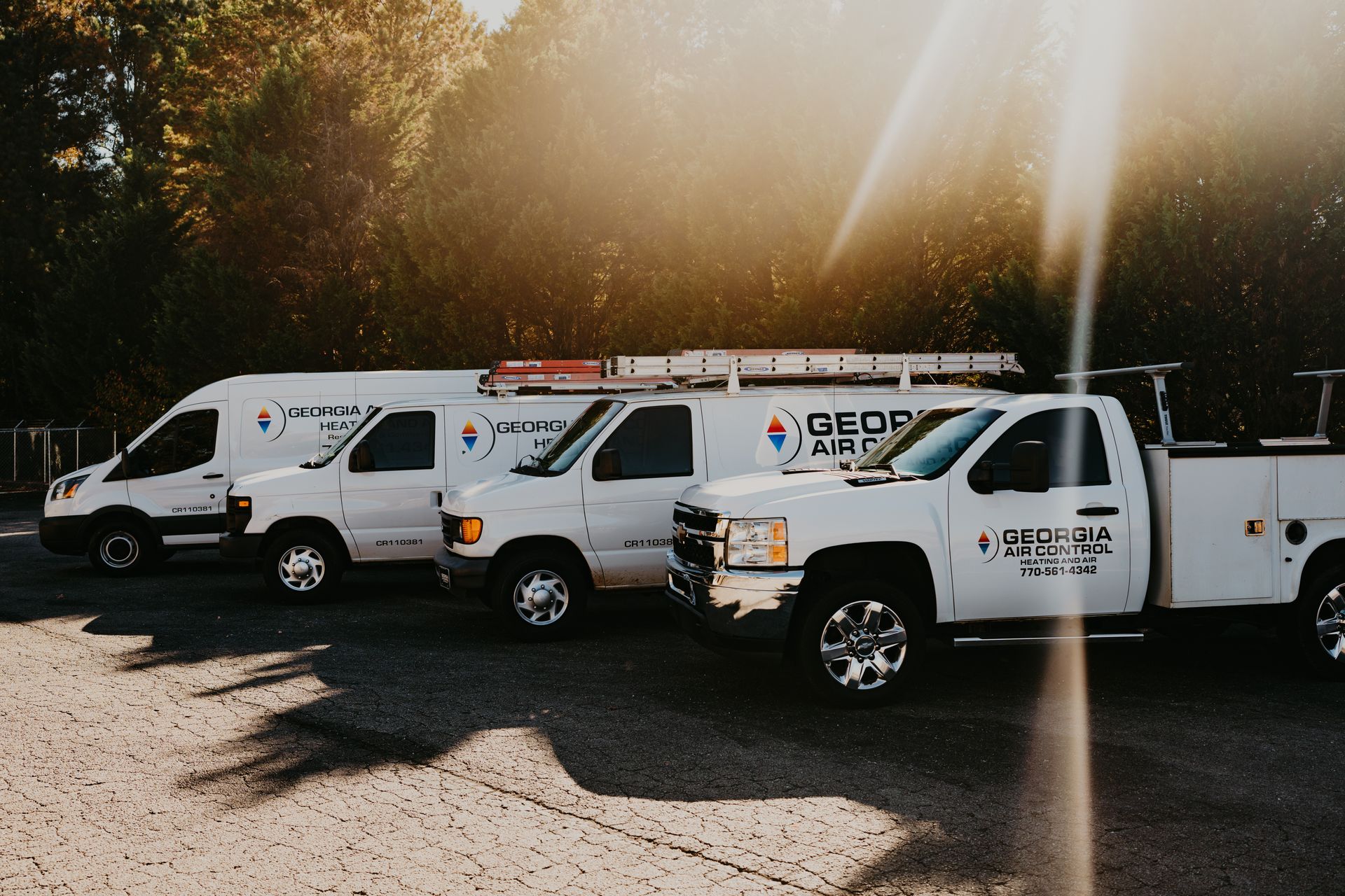 Three white trucks are parked next to each other in a parking lot.