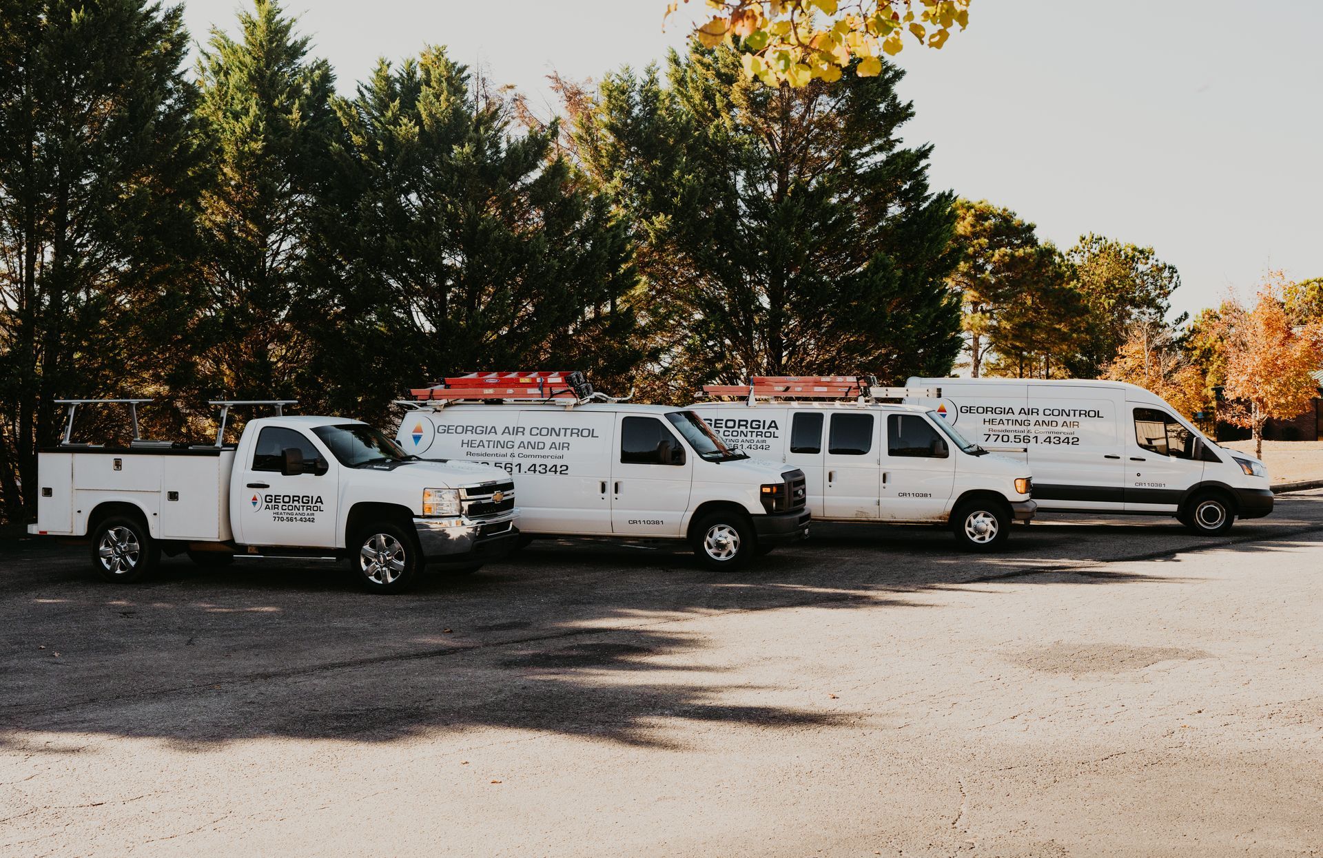 Three white trucks are parked in a parking lot