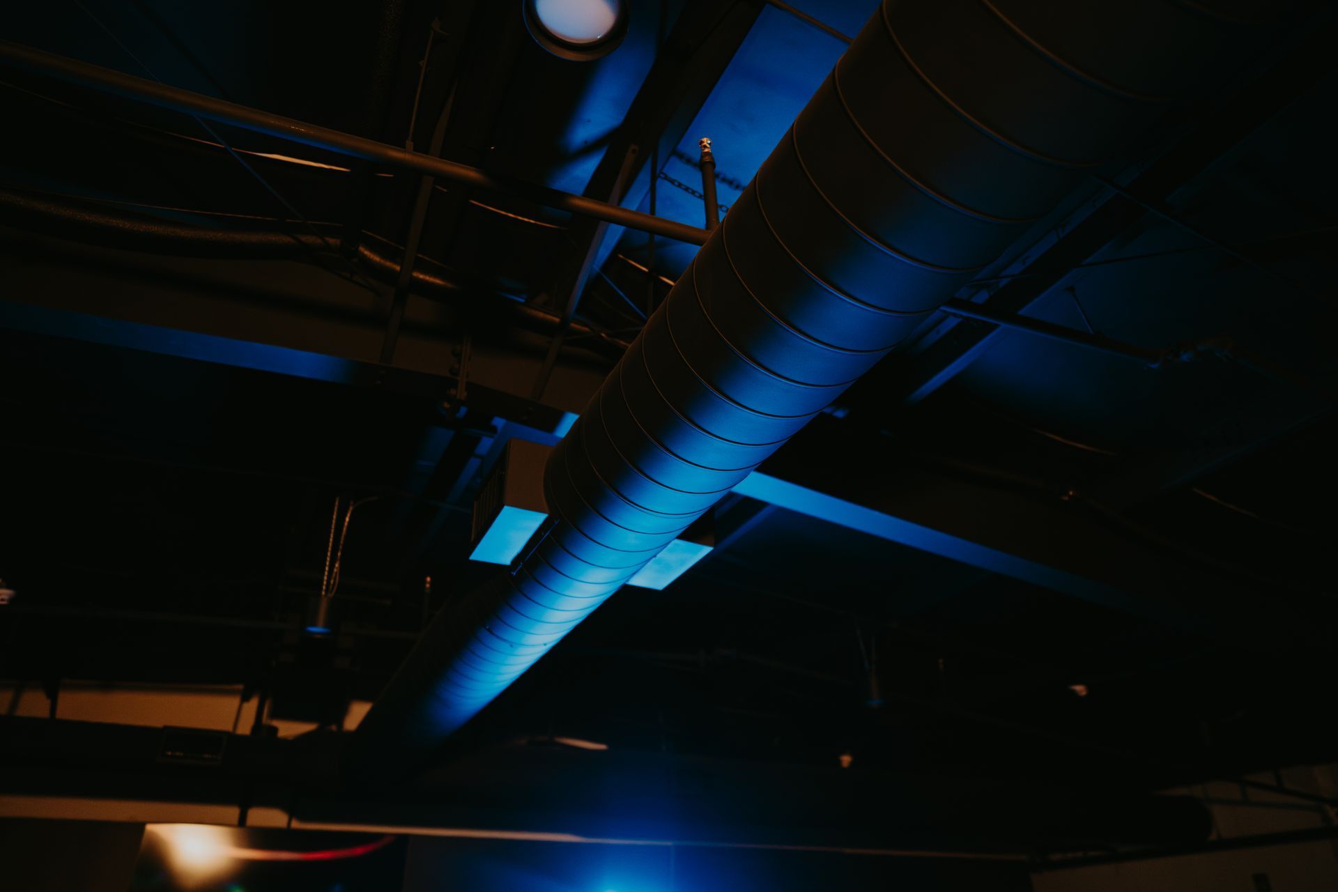 A blue light is shining on a pipe in a dark room.