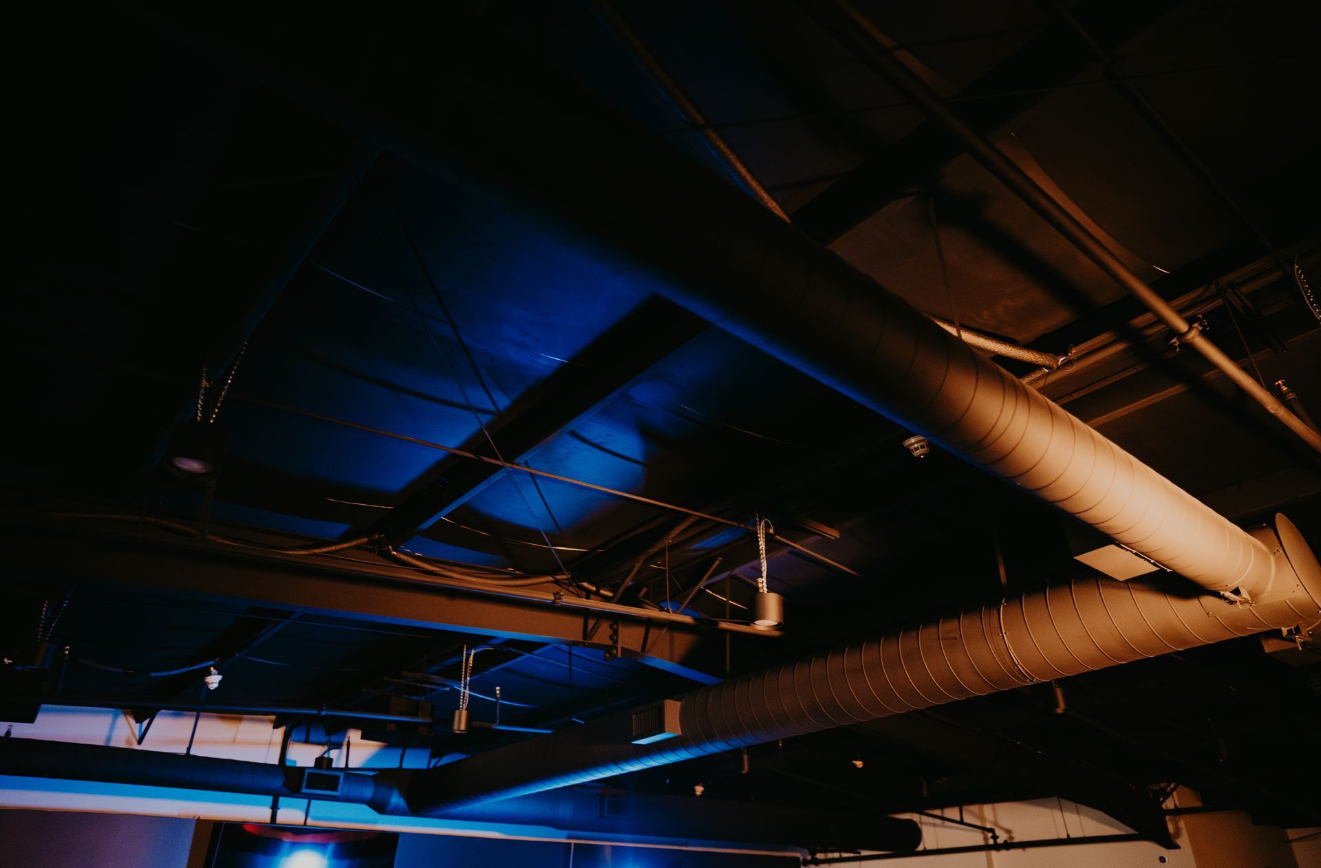 A dark room with a lot of pipes hanging from the ceiling.