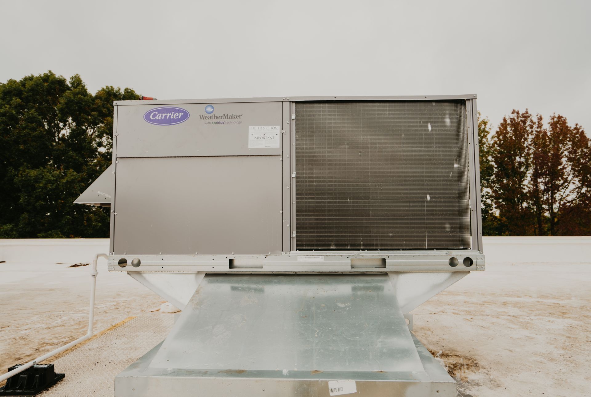 A large air conditioner is sitting on top of a white roof.