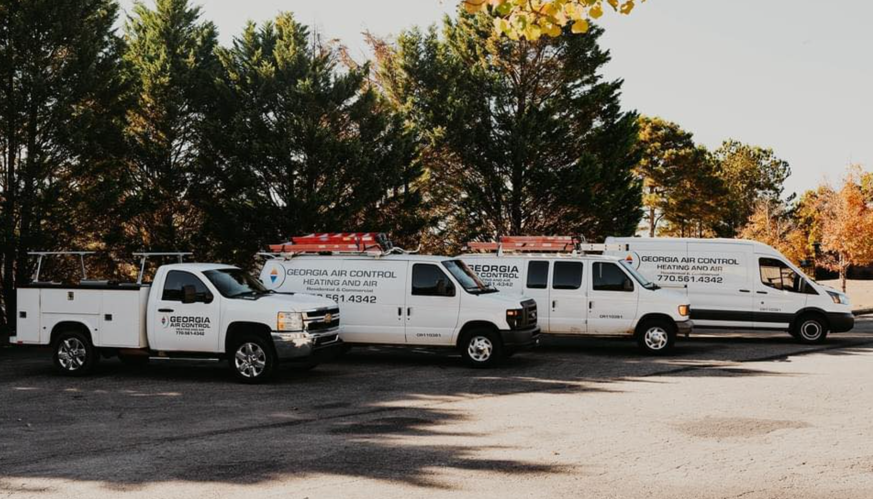 Three white trucks are parked next to each other in a parking lot