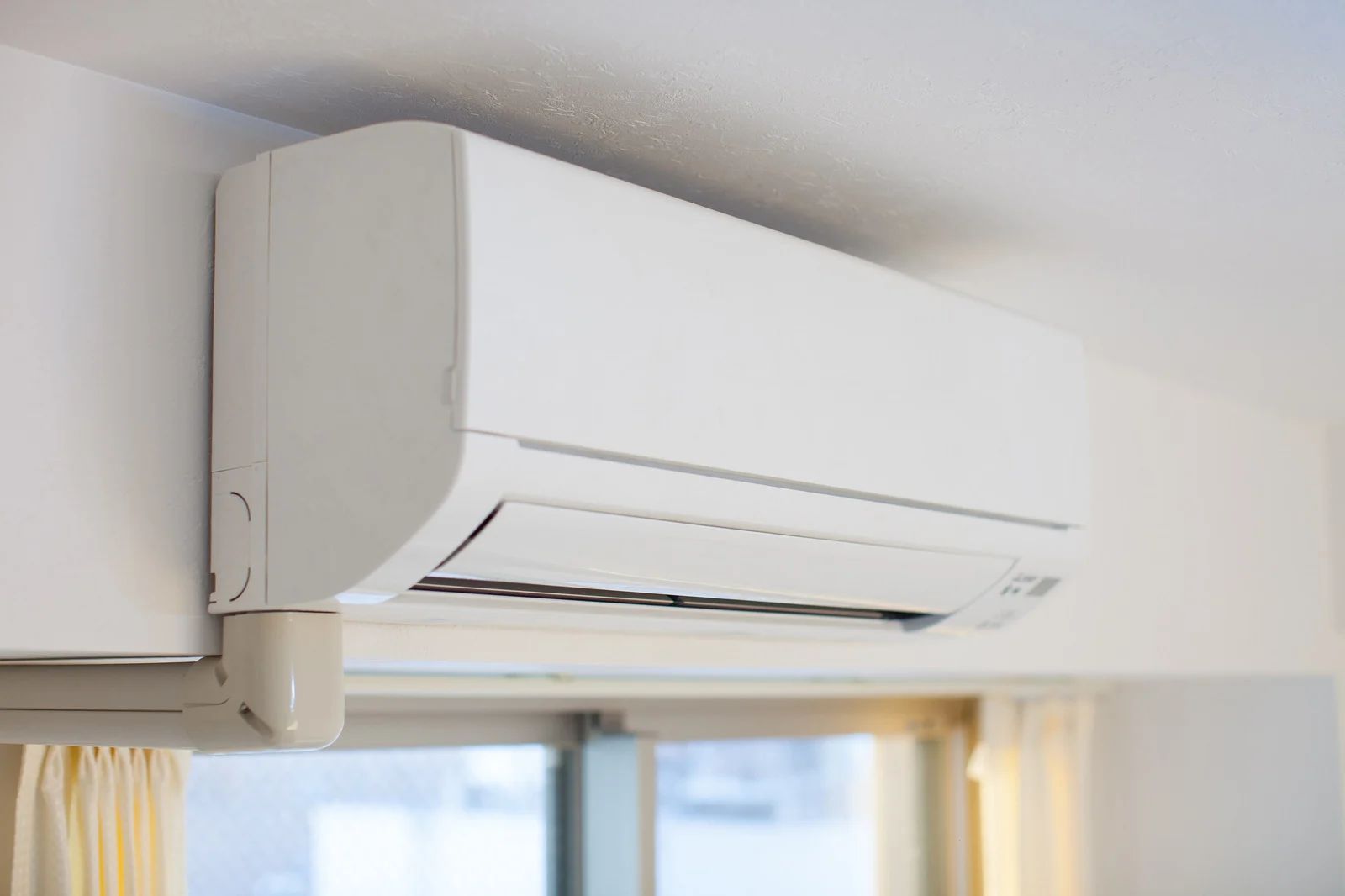 White wall-mounted air conditioner above a window.
