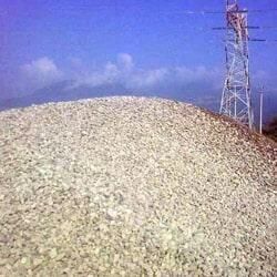 Hay un montón de grava en la cima de una colina junto a una torre de energía.