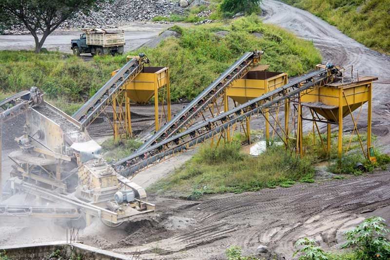 Un grupo de cintas transportadoras se encuentran sobre un campo de tierra.