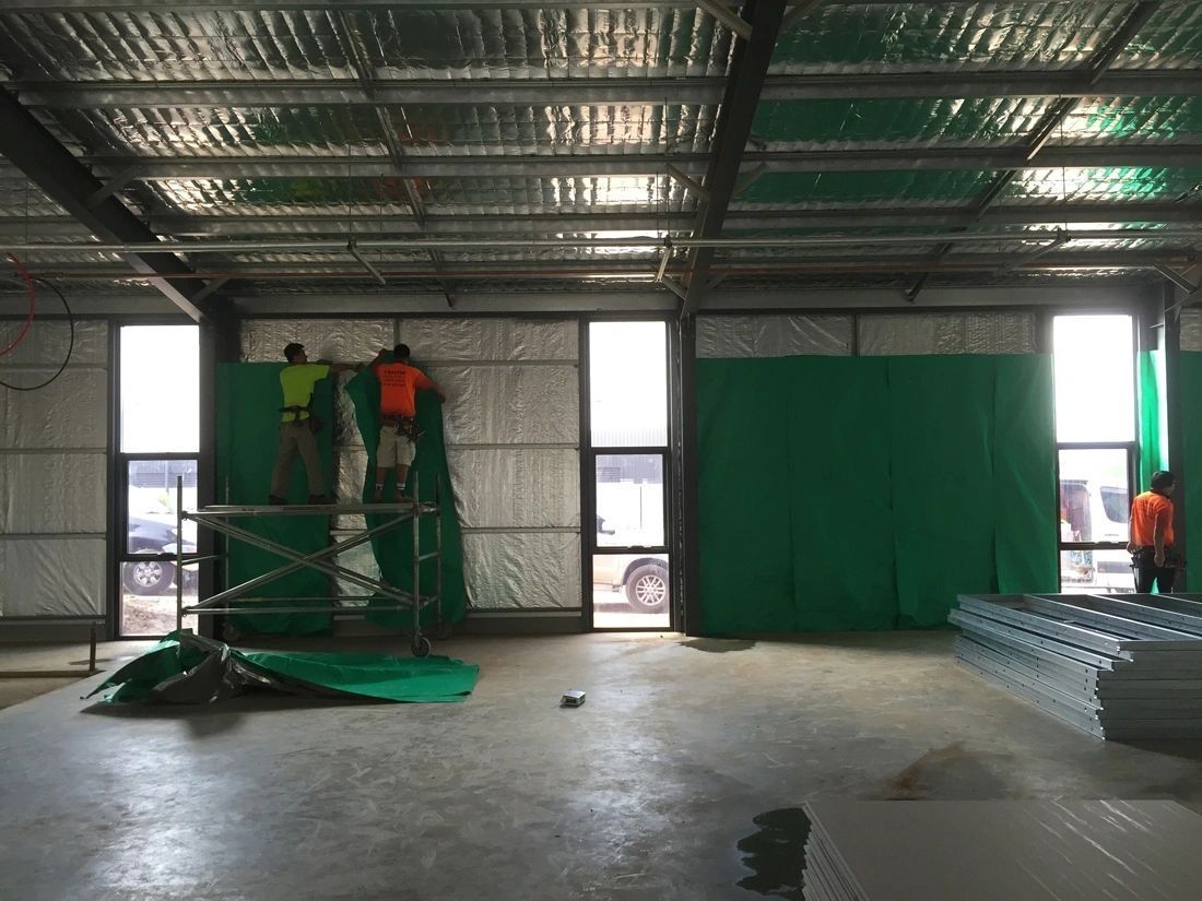 A group of people are working on a green wall in a building.