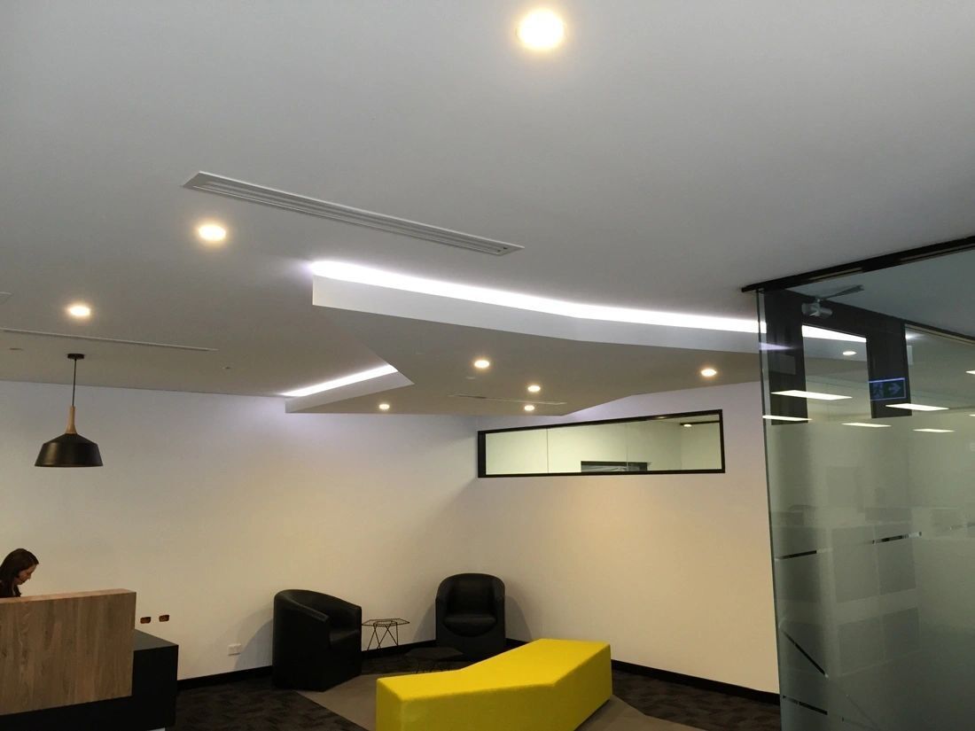 A waiting room with a yellow ottoman and chairs