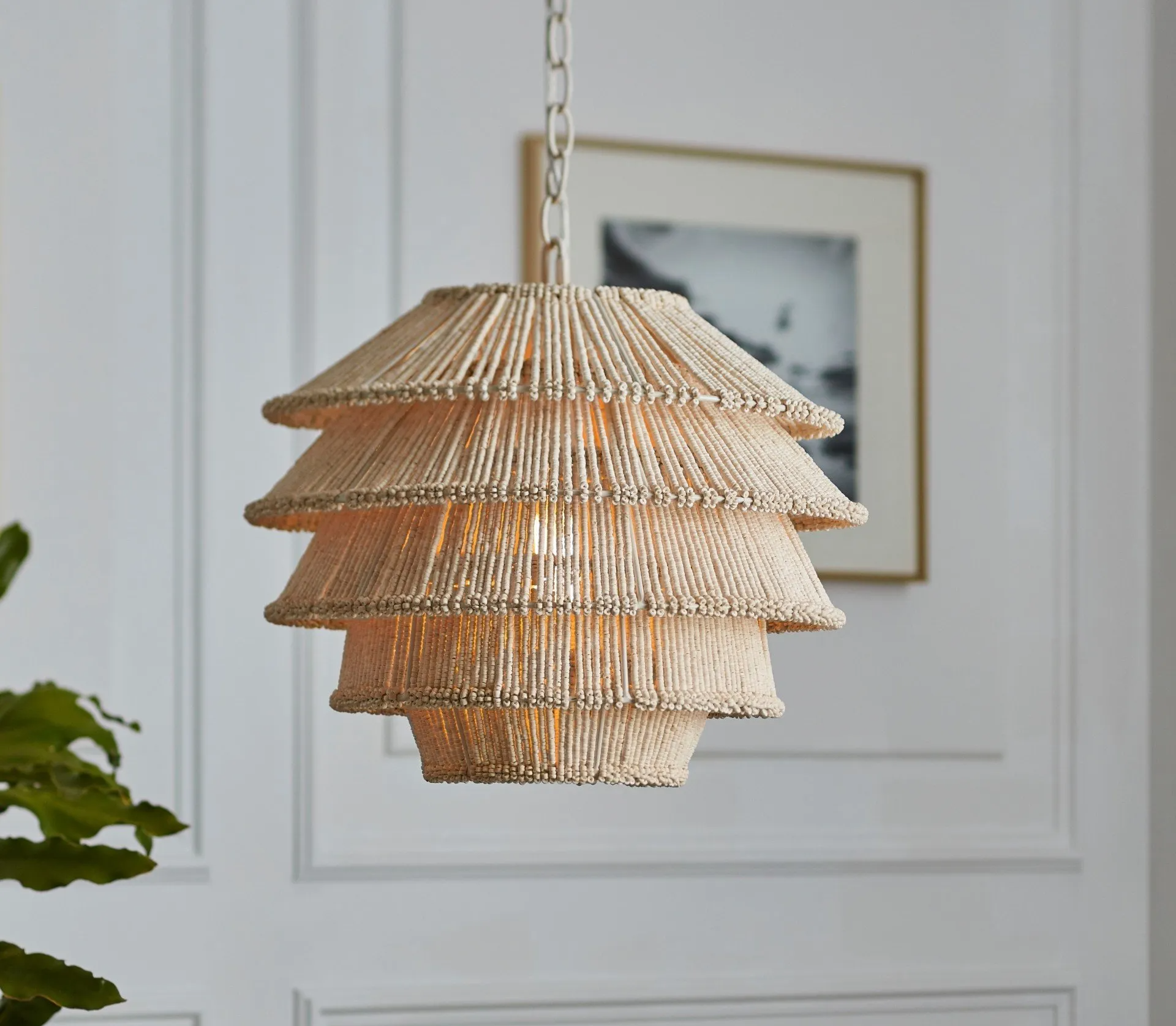 a light hanging from a chain in front of a picture