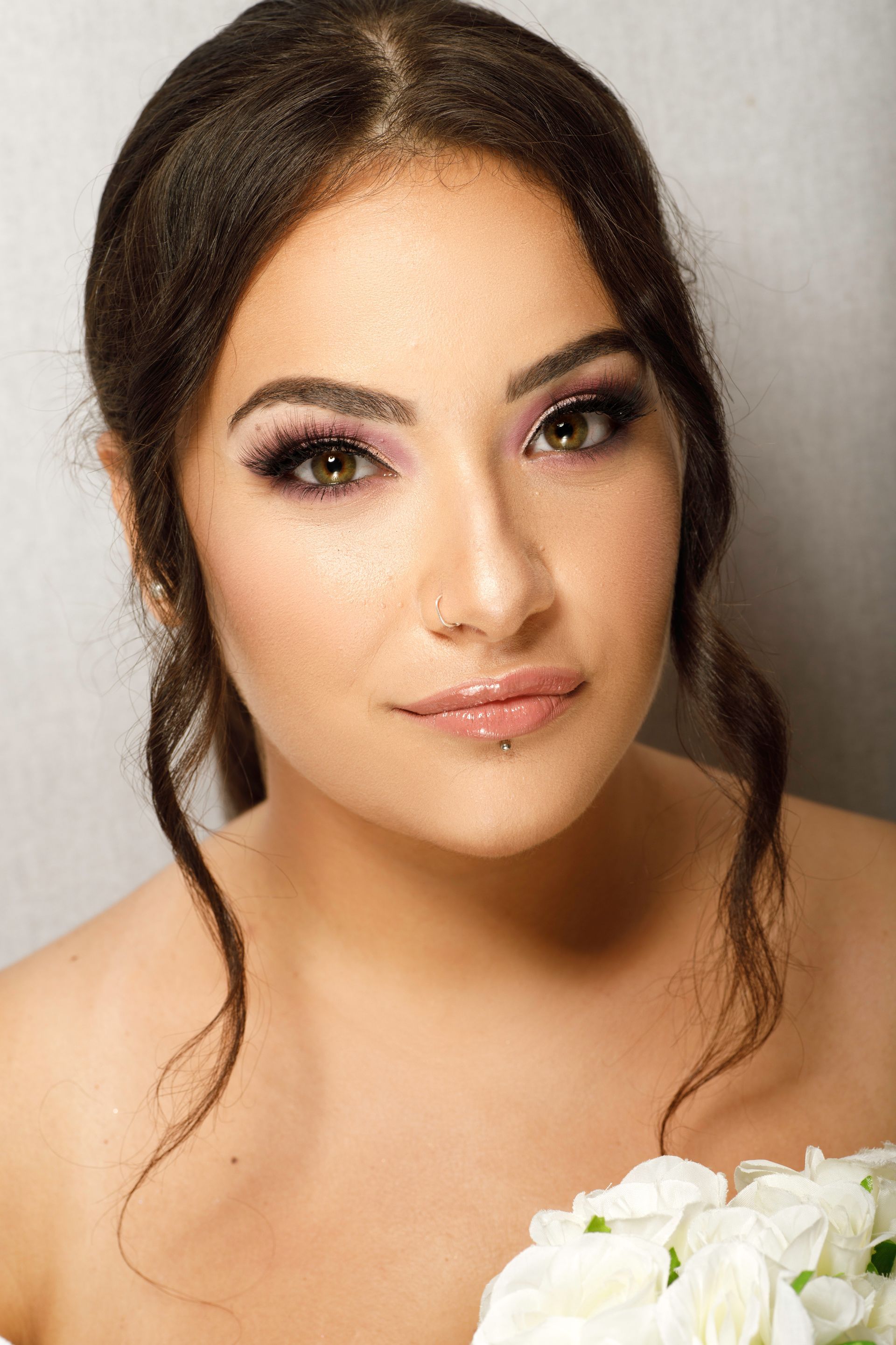 Donna con i capelli scuri, truccata, che guarda verso la telecamera.