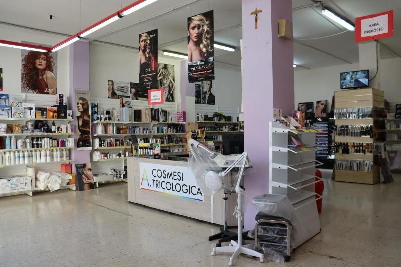 Vista interna di un negozio di cosmetici e prodotti per capelli, con scaffali, poster e un bancone.
