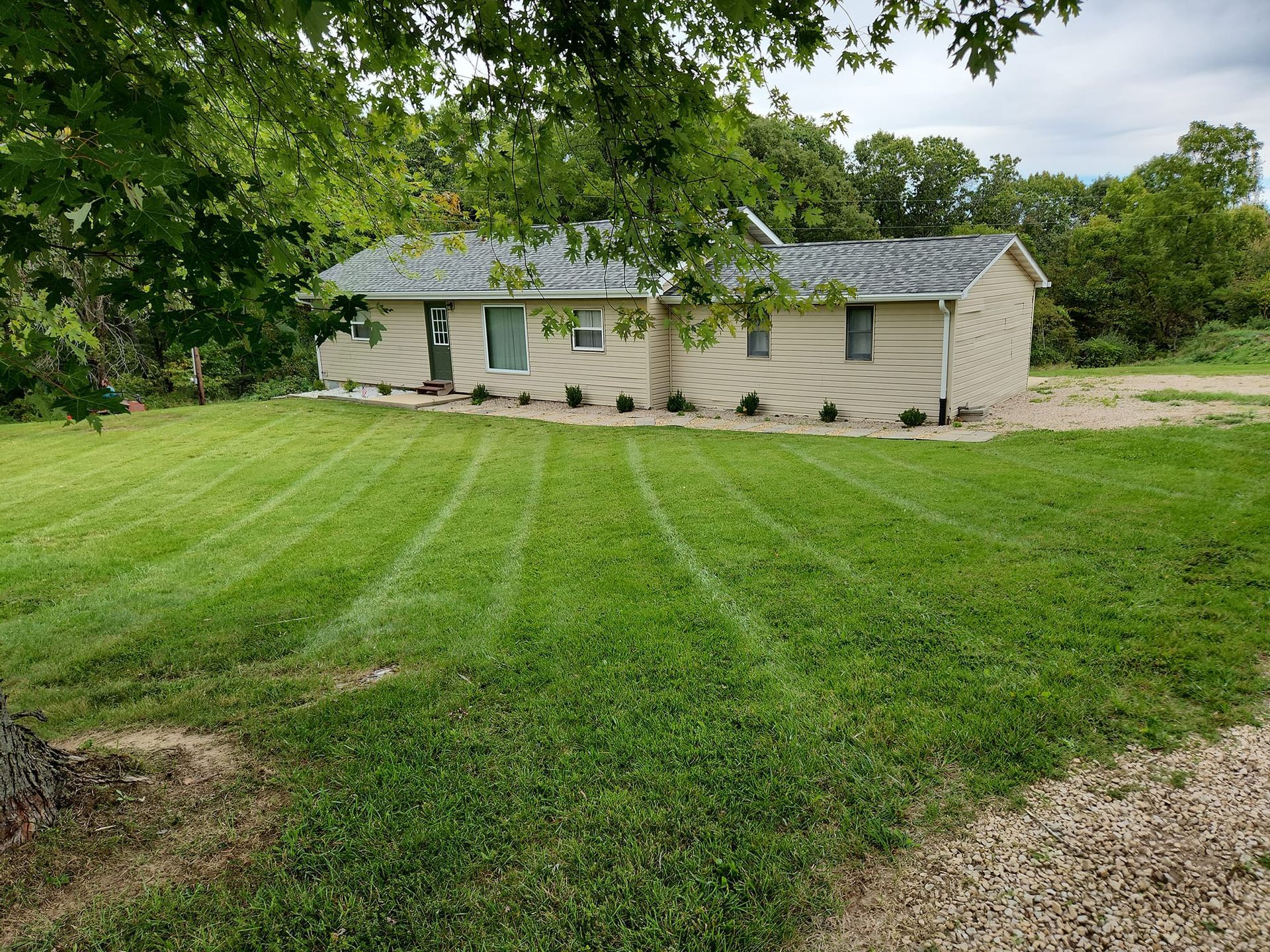 A house is sitting in the middle of a lush green field.