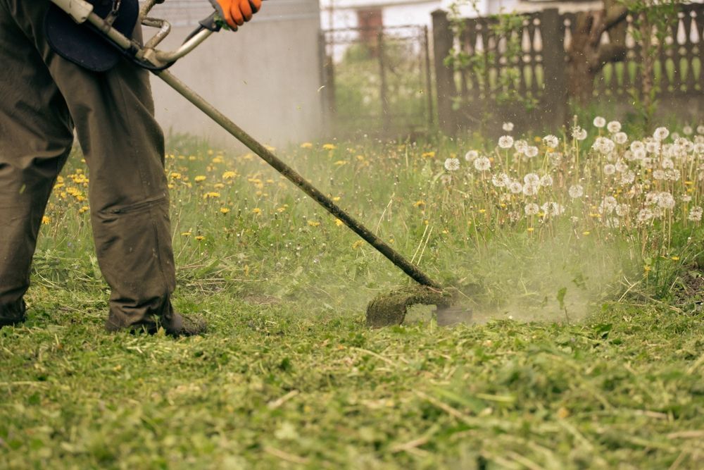 A man is mowing the grass with a lawn mower.